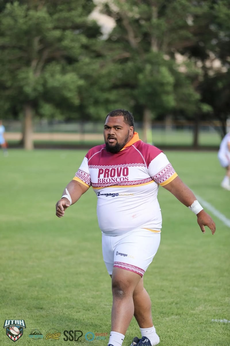Broncos player in white and maroon walking mid-field with taped wrists