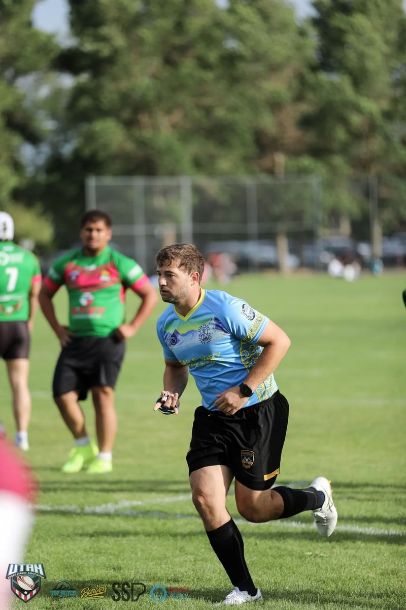 Match official in a light blue shirt jogs into position among green-jerseyed players
