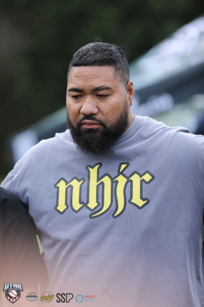 Bearded squad member in a gray tee locks arms in the post-match huddle
