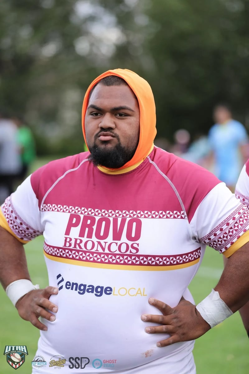 Provo Broncos player in white and maroon jersey and orange scrum cap standing with hands on hips before the game