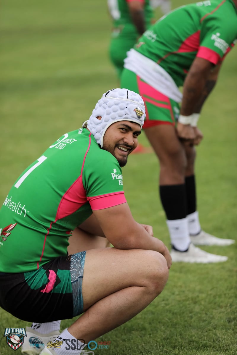 A scrum-capped Bluffdale Rabbitahz player in green crouches at the mark during a stoppage.