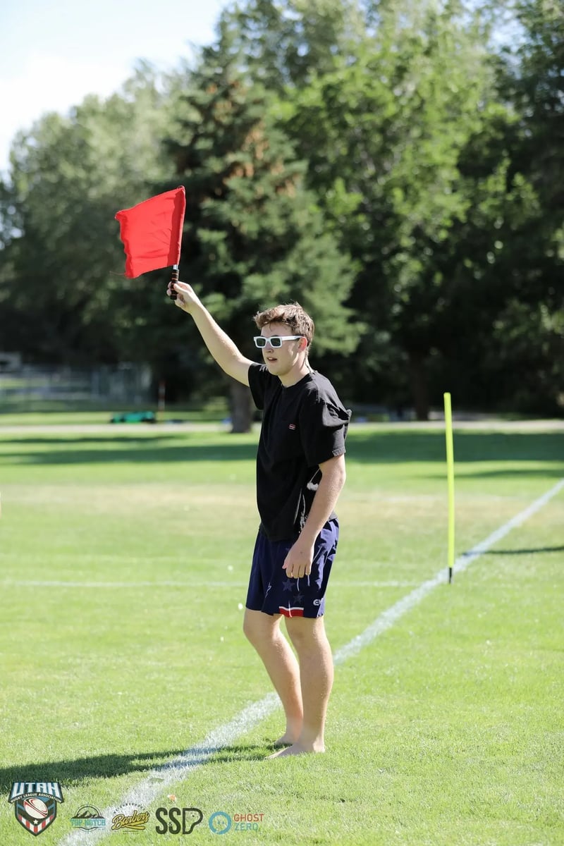 Touch judge in sunglasses raises a red flag on the sunlit sideline