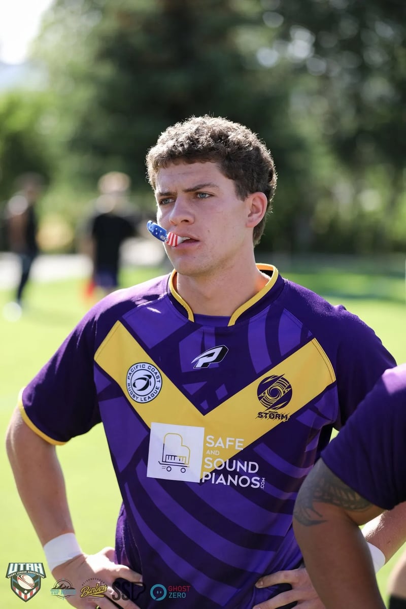 Player in a purple-and-gold jersey with a stars-and-stripes mouthguard catches his breath between plays