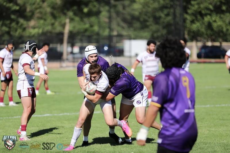 Lehi Raiders defenders in purple wrap up a Riverton Seagulls ballcarrier in white and maroon.