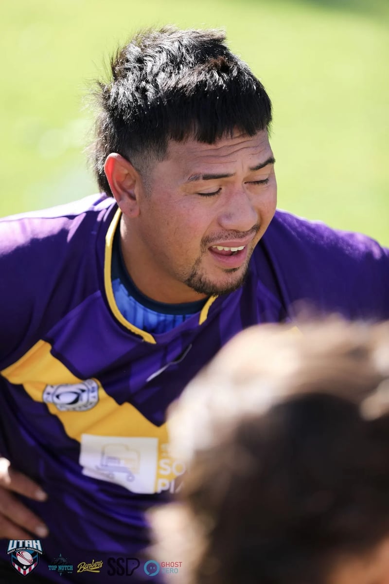Candid close-up of a smiling Raiders player in a purple and gold jersey on the sideline.