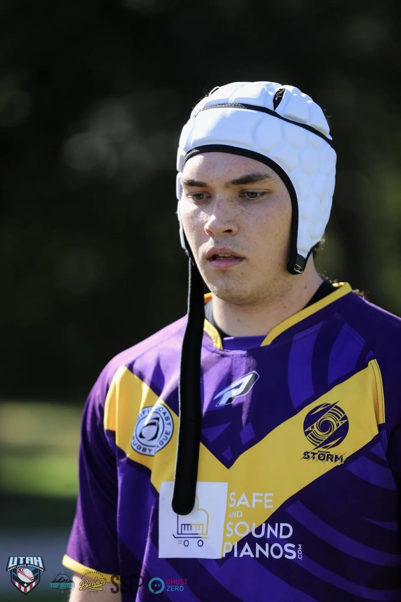 Young Raiders player in a white scrum cap and purple jersey listens intently during a break in play.