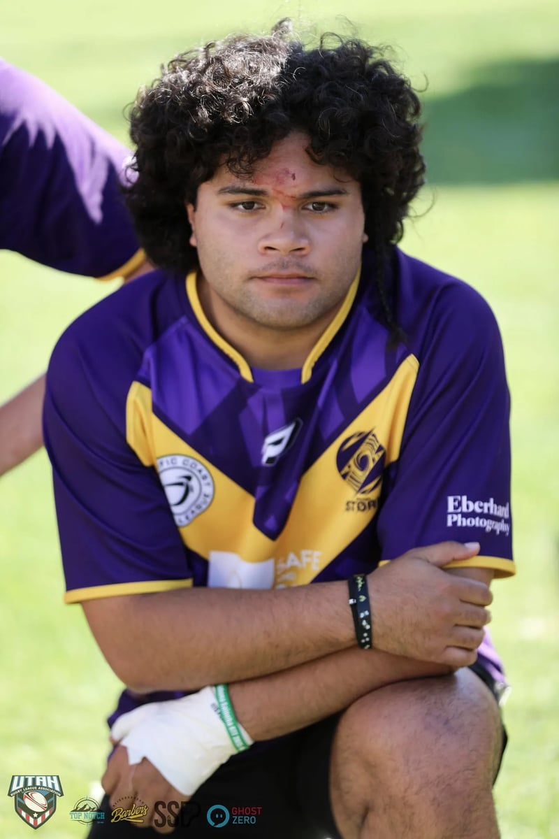 Long-haired Raiders player stands with arms crossed in his purple and gold jersey during a team gathering.