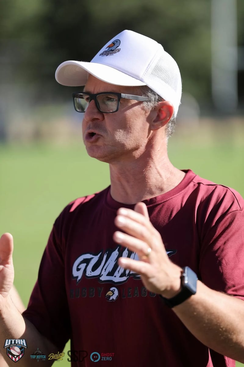 A coach in a maroon tee gestures mid-speech while addressing the Seagulls during a sideline team talk.