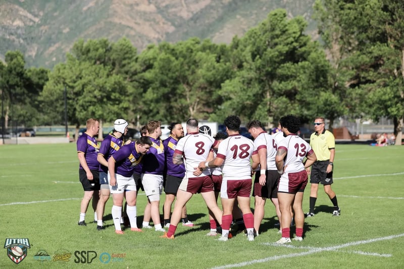 Forwards in white and maroon and purple and gold pack down together at close quarters on the field.