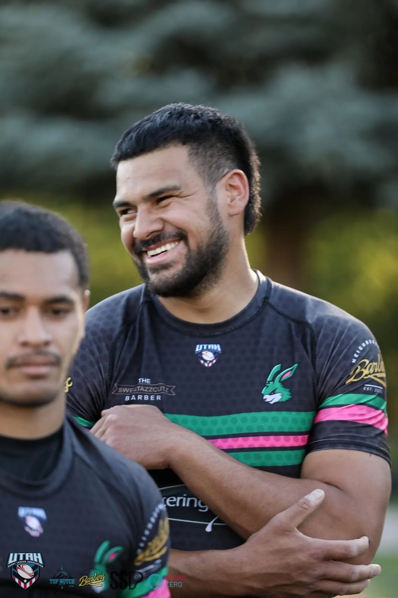 Two Rabbitahz players in black jerseys with green and pink trim share a laugh after the match, a smiling teammate behind them.