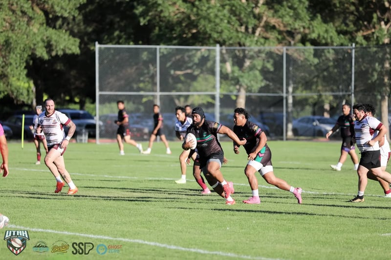 A Rabbitahz forward in headgear carries the ball into the Seagulls defensive line, a support runner in black on his shoulder and defenders in white and maroon closing from both sides.