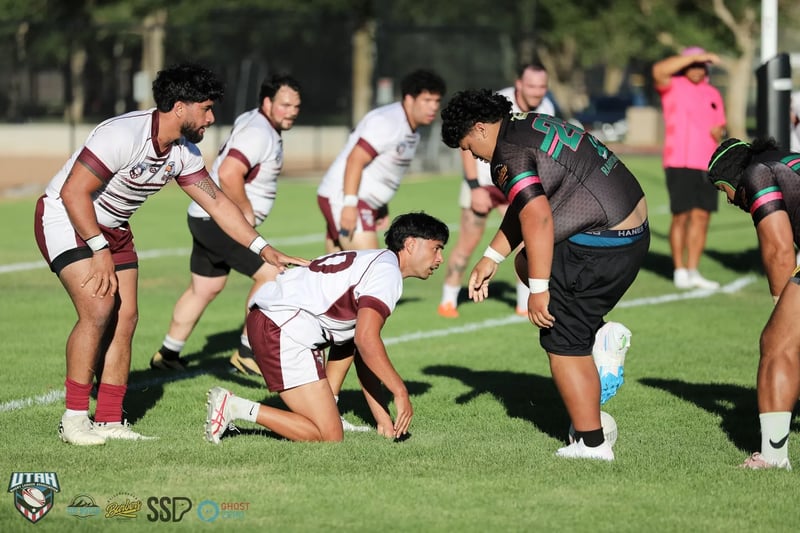 A Seagulls player in white and maroon plays the ball on all fours as a large Rabbitahz marker in black with green and pink trim stands over him, Seagulls teammates lined up behind.