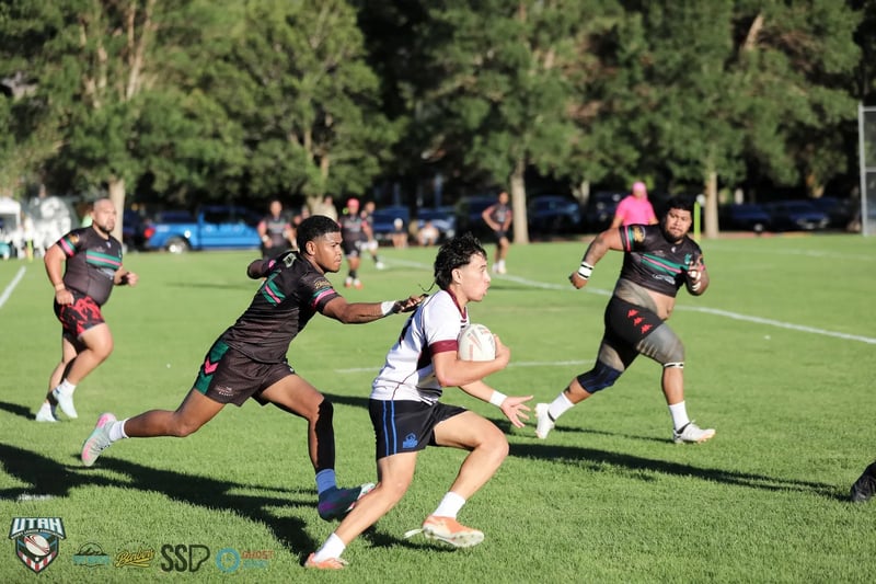 A Seagulls runner in white and maroon weaves between two Rabbitahz defenders in black, green and red kit with the ball tucked under one arm.