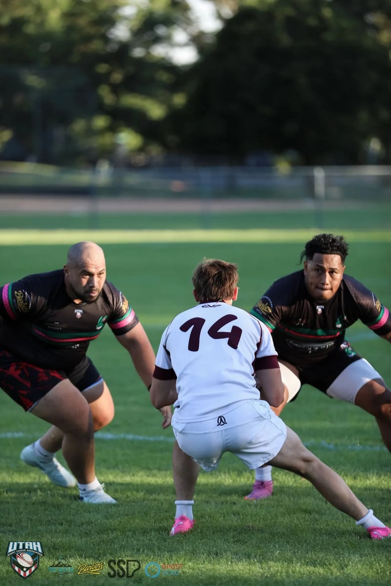 A Seagulls player in white number 14 squares up between two Rabbitahz forwards in dark kit in low golden evening light.