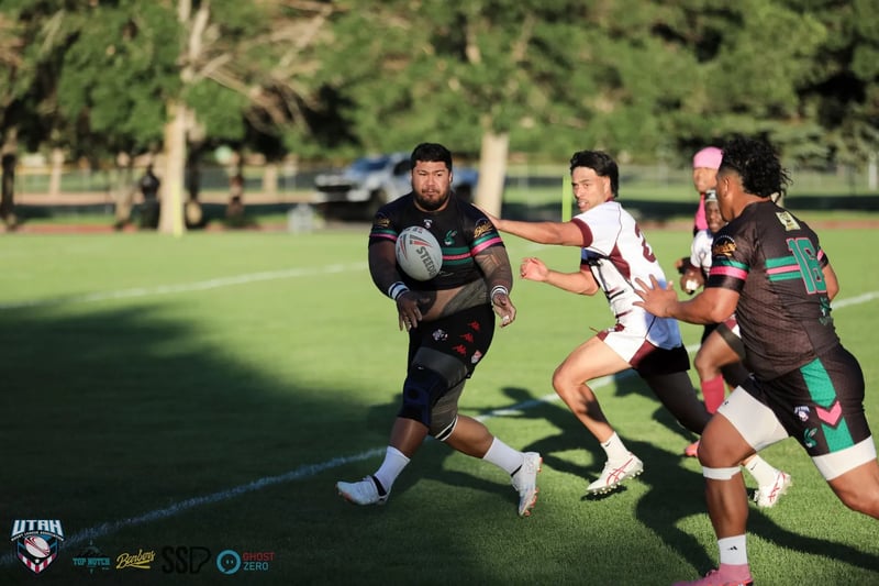 A Rabbitahz carrier in black, green and red kit sprints clear with the ball as two Seagulls chasers in white and maroon give pursuit in golden light.