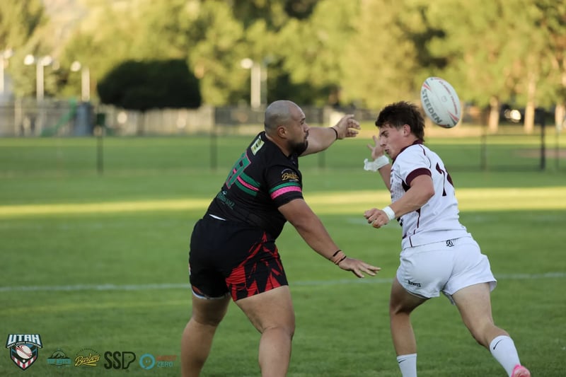 A Rabbitahz playmaker in dark kit fires a pass with the ball frozen mid-air as a Seagulls defender in white rushes up.