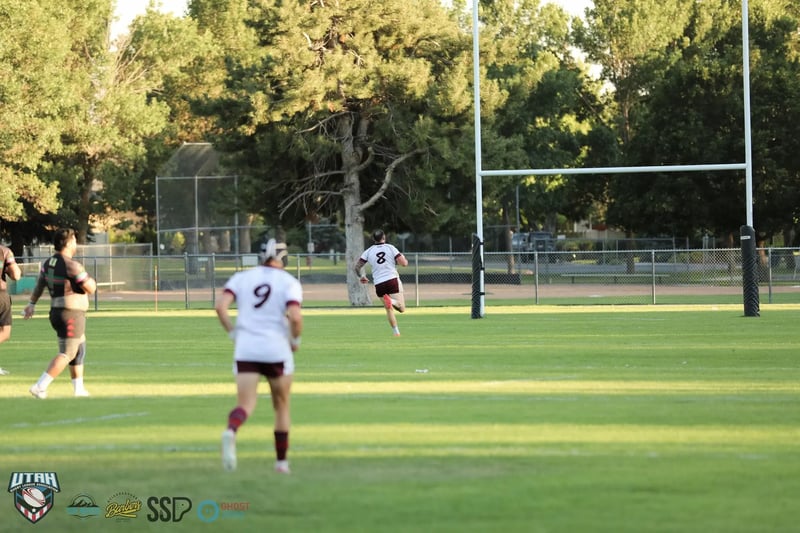 A Seagulls player in white and maroon, number 9, runs upfield toward the goal posts with a dark-kitted Rabbitahz player trailing on the open pitch.