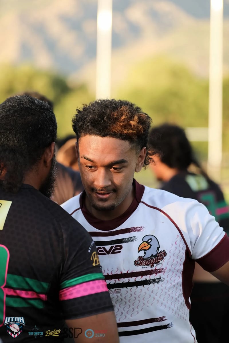A smiling Seagulls player in white and maroon chats with Rabbitahz opponents in dark green-trimmed jerseys during post-match mingling.