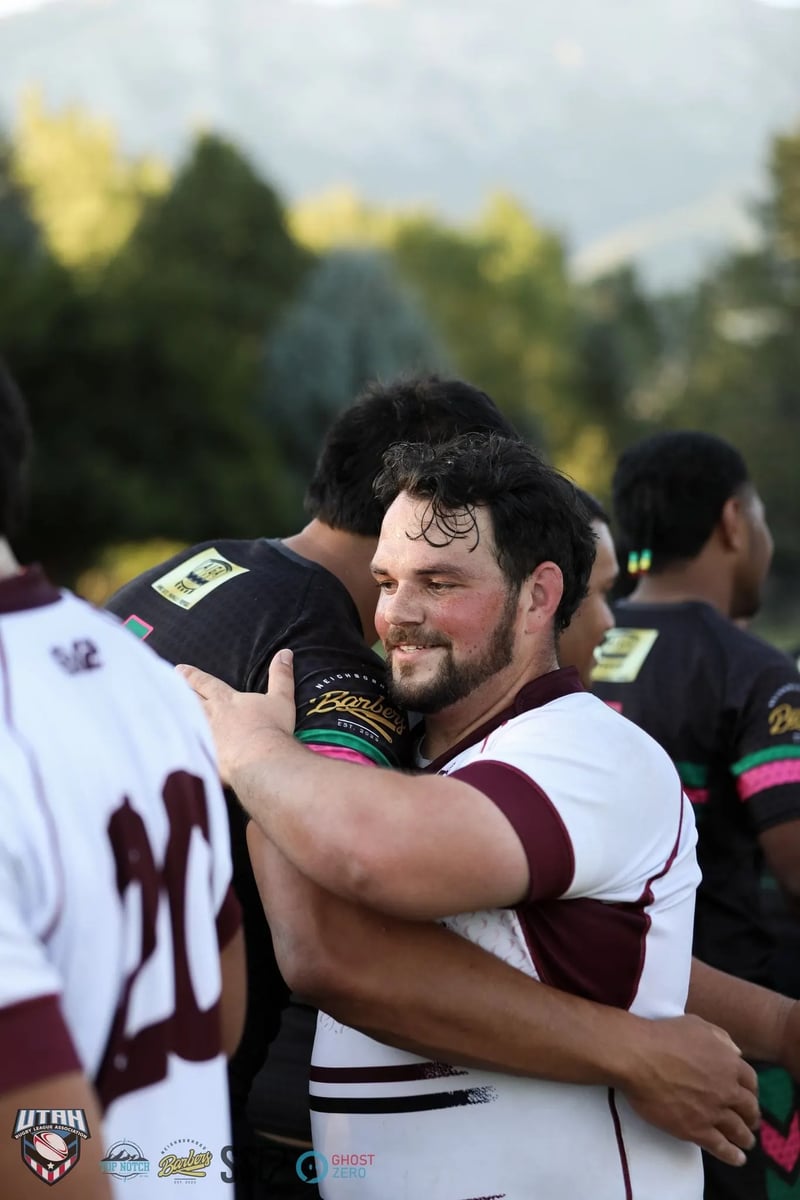 A grinning bearded Seagulls player in white embraces a Rabbitahz opponent in a dark green-and-red kit in a post-match hug.