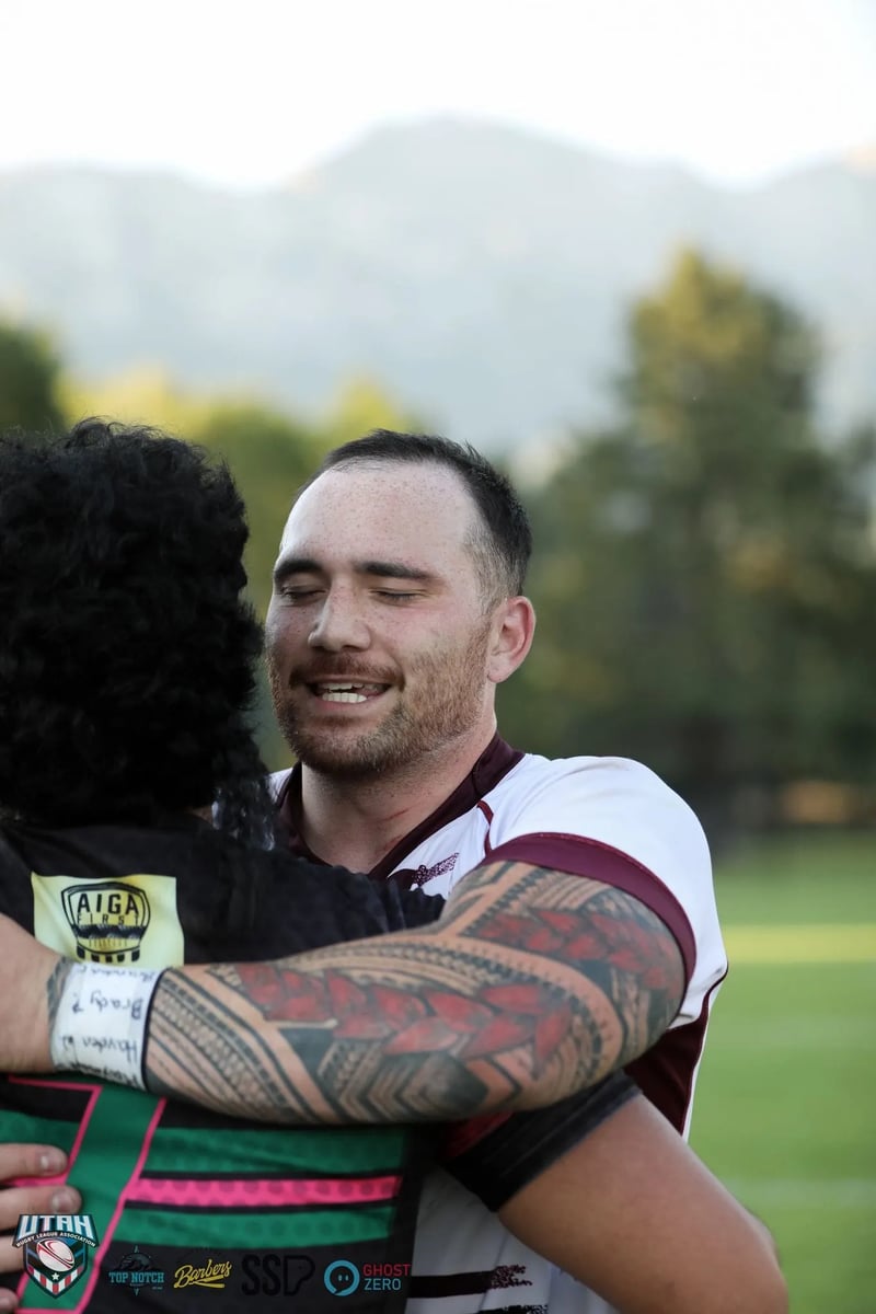 A smiling Seagulls player in a white and maroon jersey embraces an opponent during the post-match handshakes.