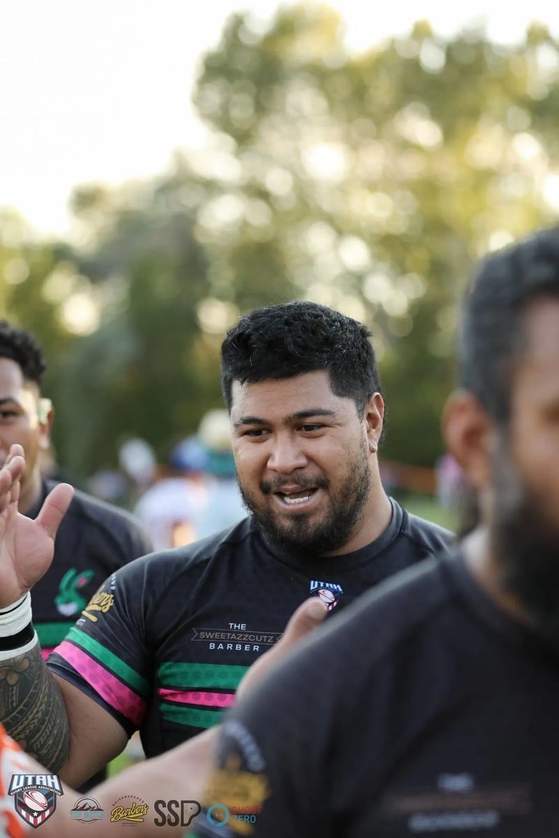 A laughing Rabbitahz player in a dark green-trimmed jersey shares a joke with teammates during the post-match celebrations.