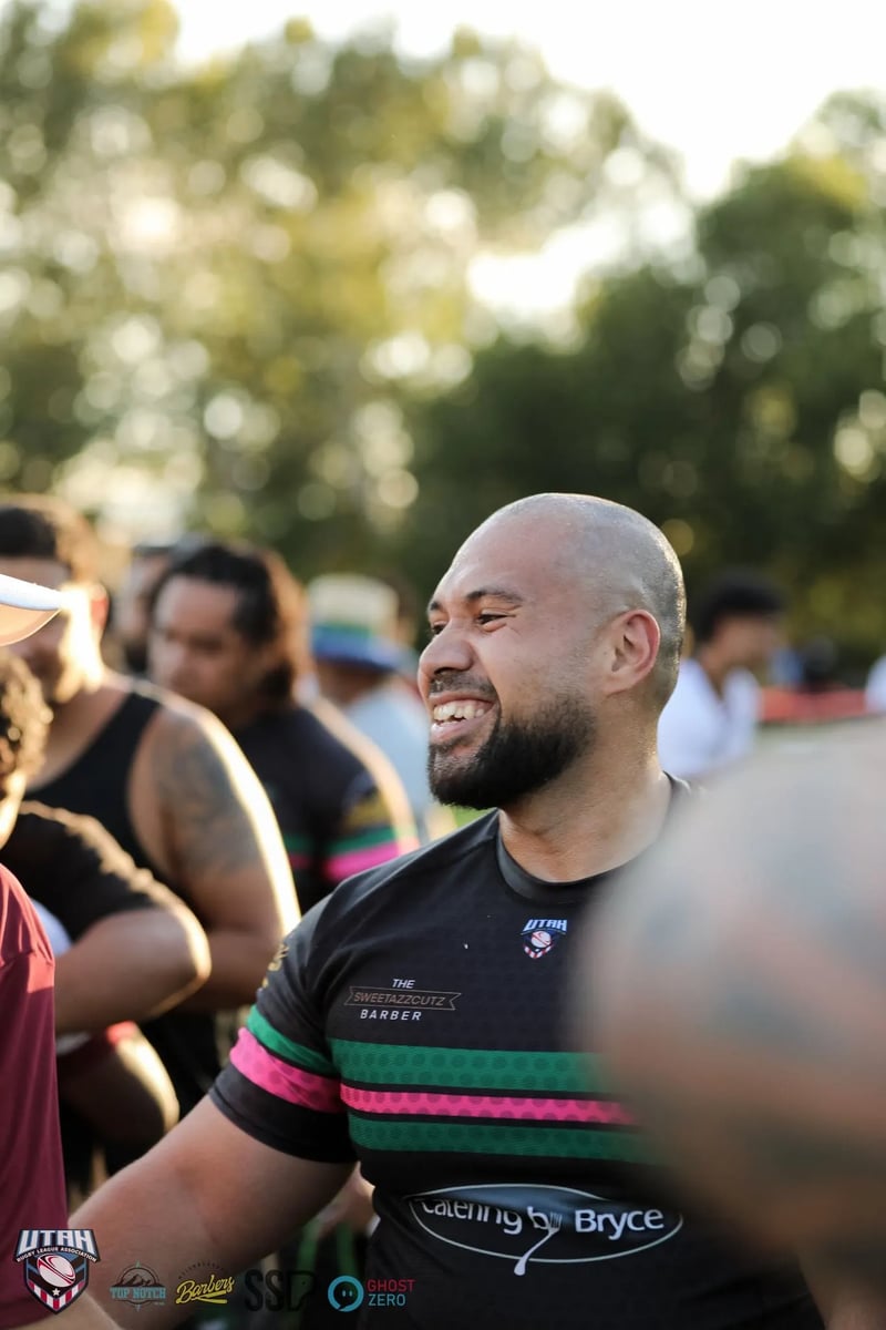 A smiling Rabbitahz player in a black jersey laughs with teammates in low golden light after the match.