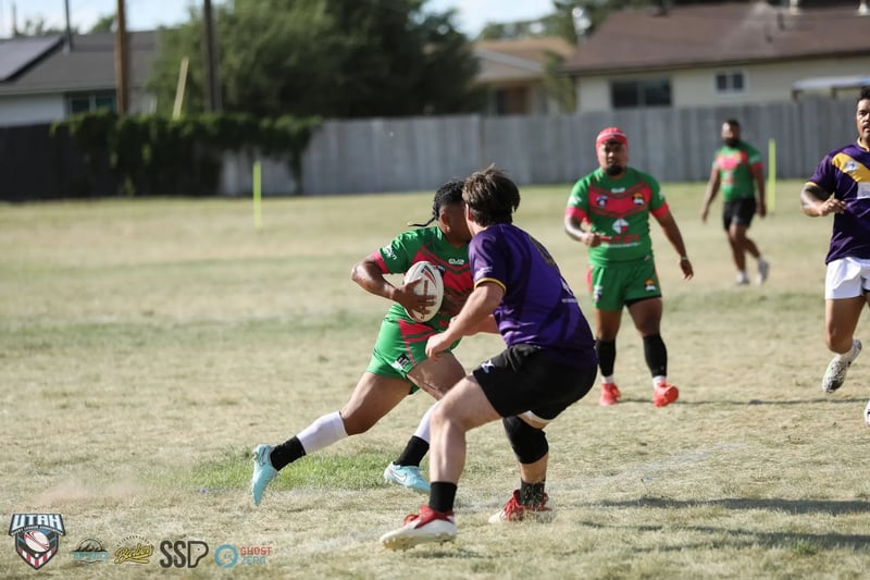 Rabbitahz ball carrier in green and red steps off his right foot to beat a closing Raiders defender in purple, a teammate in a red scrum cap in support behind the play.