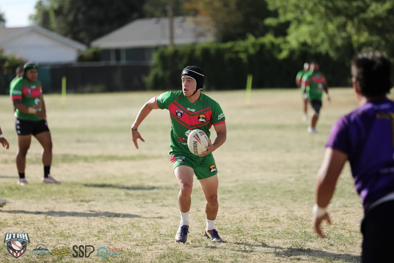 A scrum-capped Bluffdale Rabbitahz playmaker in green shapes to pass with a Lehi Raiders defender closing.