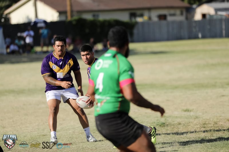 A Bluffdale Rabbitahz forward in green carries the ball forward past a Lehi Raiders defender in purple.