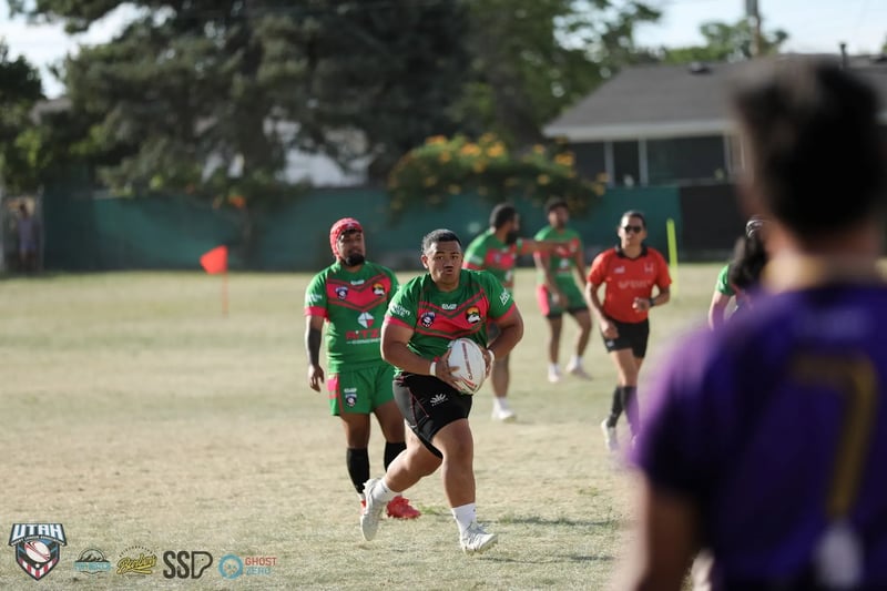 Rabbitahz ball carrier in a red headguard runs with the ball, framed past the out-of-focus shoulder of a Raiders player in purple
