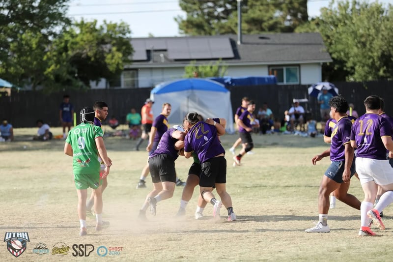 Dust kicks up from the dry field as Rabbitahz players in green and red and Raiders players in purple collide in a tackle
