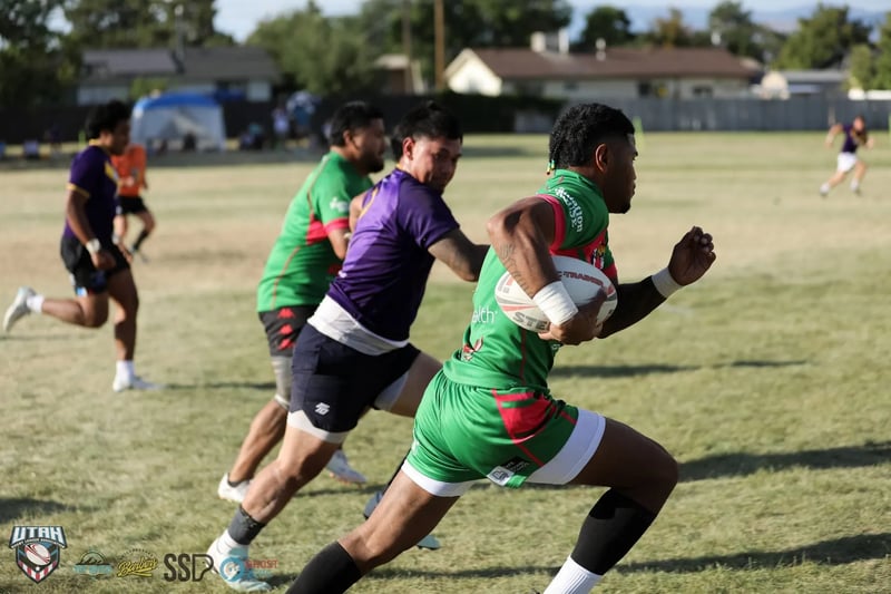 Rabbitahz ball carrier in green and red bursts upfield with the ball as Raiders defenders in purple chase behind