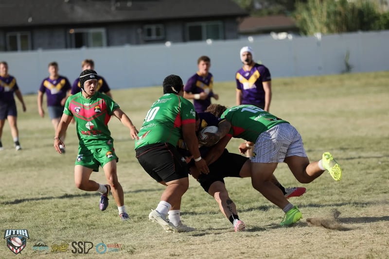 Rabbitahz players in green and red combine in a heavy wrap tackle on a Raiders ball carrier