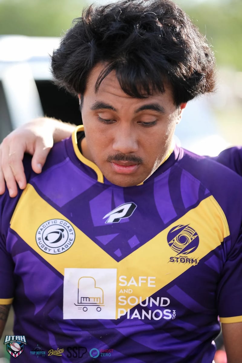 Raiders player in purple and gold bows his head as a teammate's arm rests on his shoulder after the match