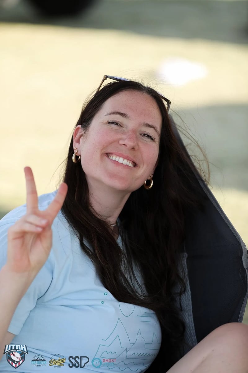 Smiling spectator flashes a peace sign from the sideline shade at the festival match