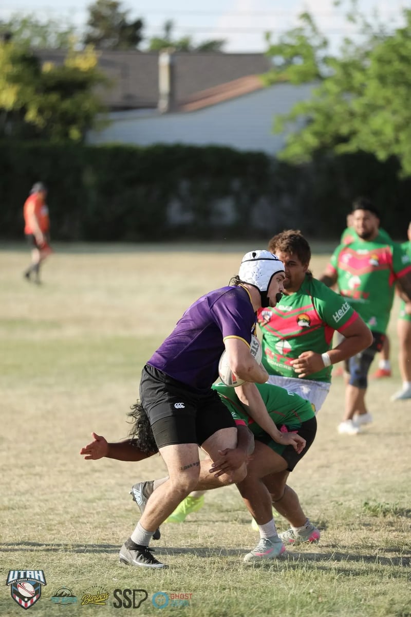 A Bluffdale Rabbitahz defender in green and red wraps up a purple-shirted Lehi Raiders ball-carrier wearing a white scrum cap at the moment of contact.