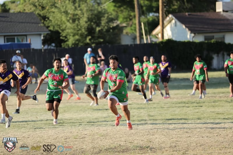Wide frame of Bluffdale Rabbitahz players in green and red sweeping downfield in numbers while Lehi Raiders defenders in purple scramble to cover.