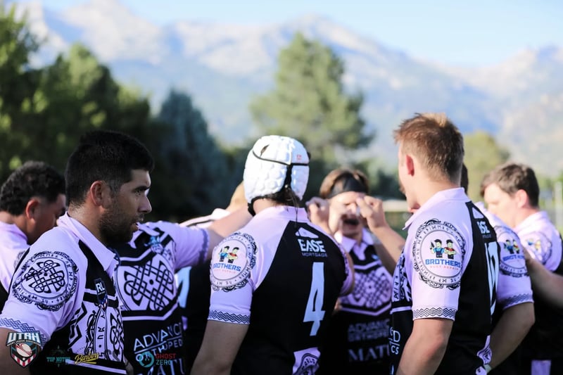 Lehi Raiders players in a huddle with arms across each other's shoulders, the Wasatch mountains behind them.