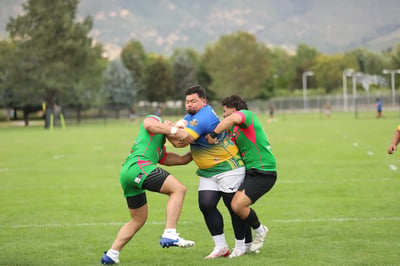 Broncos ball carrier in blue and gold wrapped up by two Rabbitahz defenders