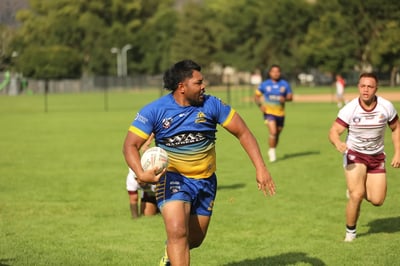 Broncos ball carrier in blue and gold sprinting into open field ahead of chasing defenders