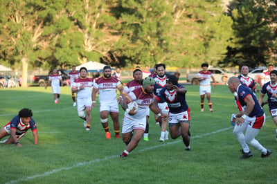 Provo ball carrier in a white and maroon kit taking on defenders in navy and red during a match