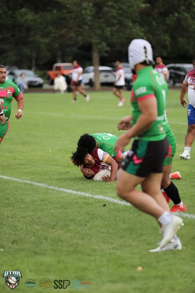 A Broncos player grounds the ball on the turf at the feet of a Rabbitahz defender