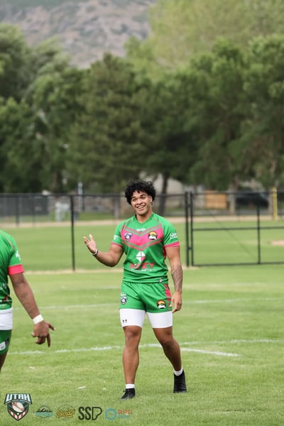 Smiling Rabbitahz player in green and red gestures toward the camera on the sideline