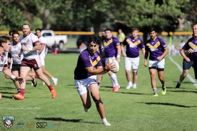 Raiders forward in purple and gold tucks the ball and charges upfield with both teams in pursuit
