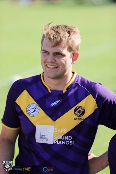 Smiling Raiders player in purple and gold on the sideline in warm evening light
