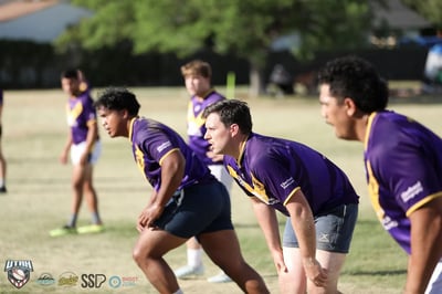 Three Raiders players in purple and gold crouch shoulder to shoulder in the defensive line, eyes up and waiting for the next play.