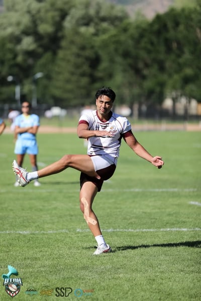 Seagulls kicker in white and maroon follows through on a goal kick with leg fully extended