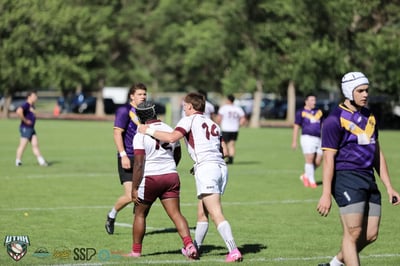 Two Seagulls teammates embrace after a score while Raiders players walk past