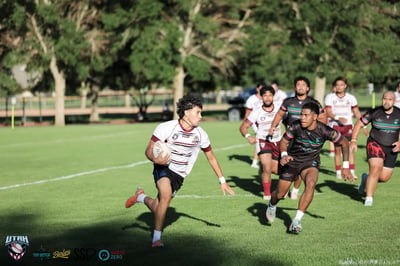 A Riverton Seagulls ball carrier in white and maroon sprints ahead of a chasing pack of Rabbitahz defenders across the open field.
